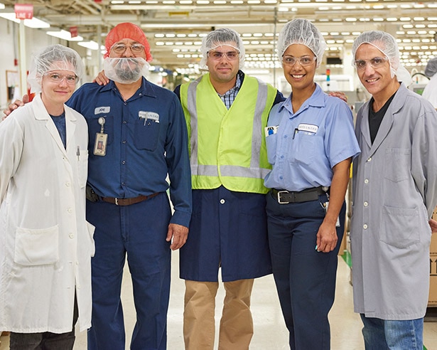 Employees wearing hair nets posing in a factory